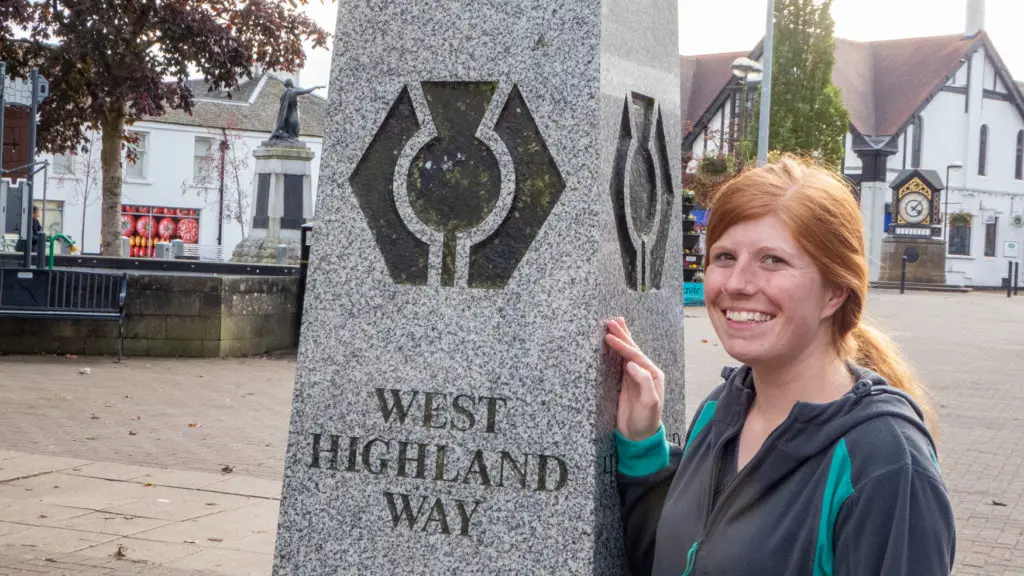 Girl stands next to West Highland Way start point. 
