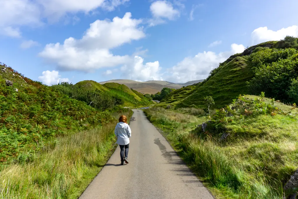 Girl walking down narrow road on Skye
